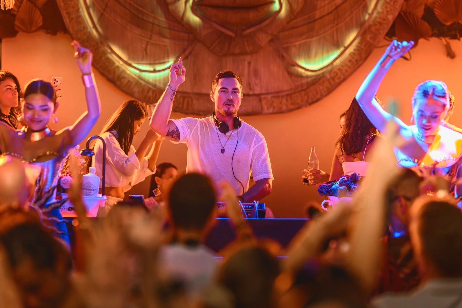 DJ playing music at a lively party with people dancing and having fun.