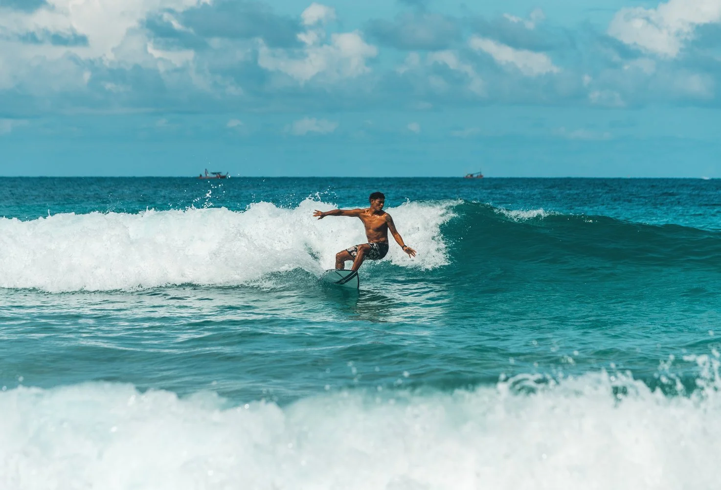 A man surfing on a wave in the ocean under a cloudy sky.