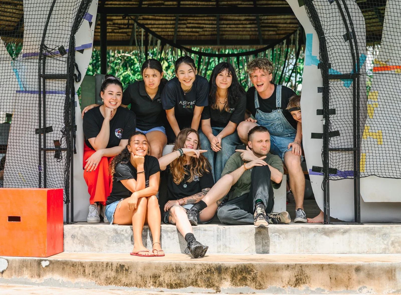 Group of teenagers and young adults posing playfully on a boat or raft structure as part of an outdoor activity or event.