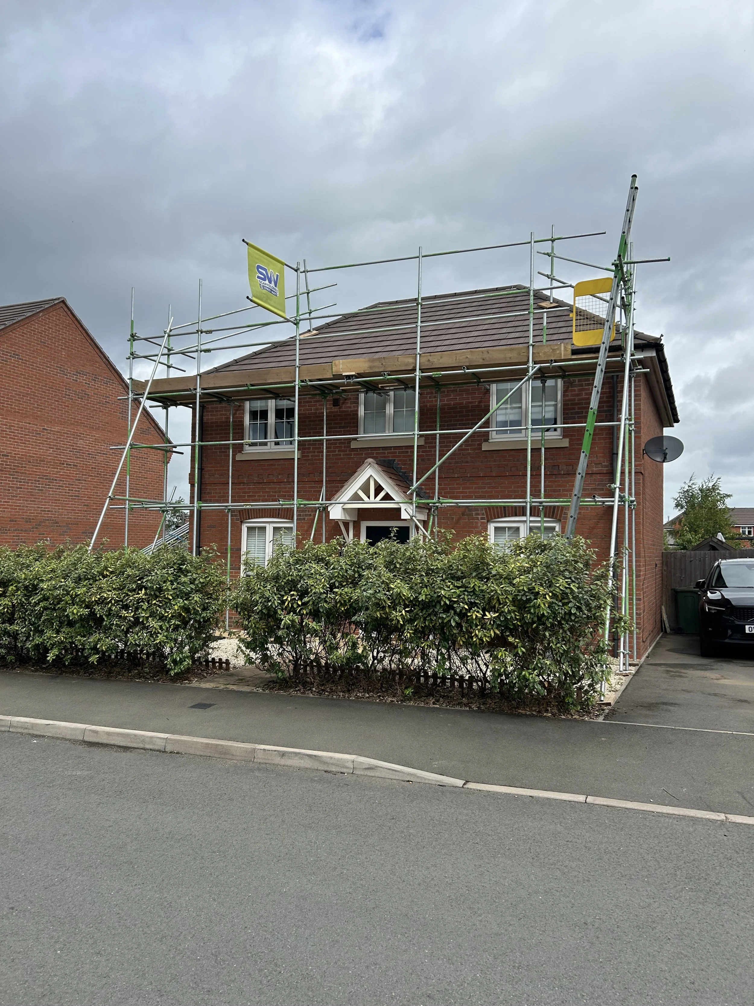 A brick house under renovation with scaffolding surrounding it. Scaffolding service from SW Scaffolding in Worcestershire, Warwickshire and South Birmingham.
