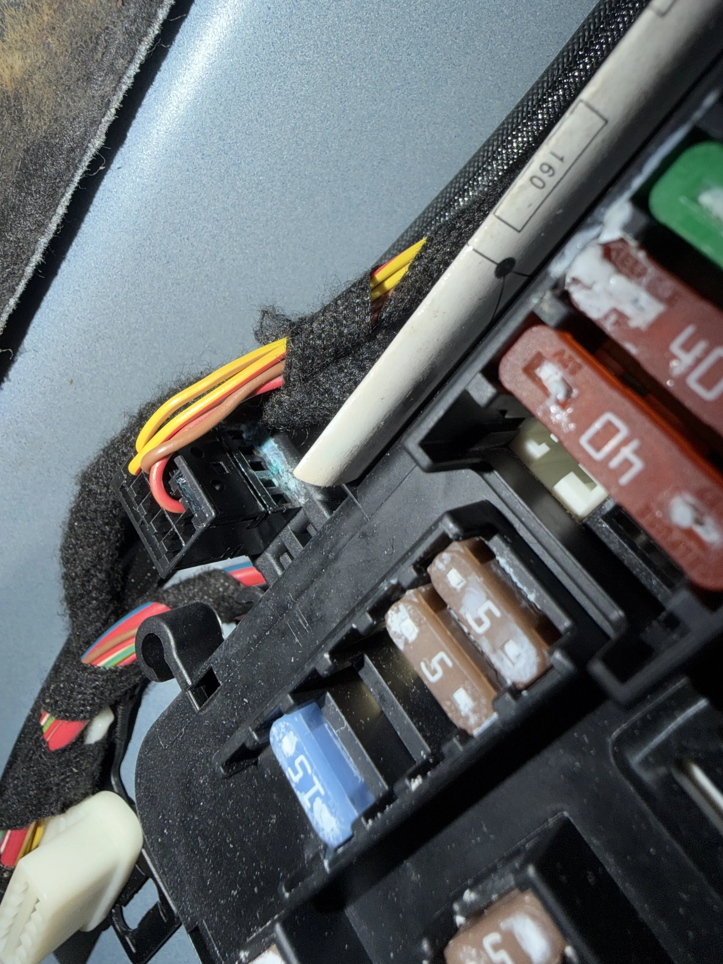 Close-up of electrical wiring and components inside a device or panel, including colored wires, resistors or fuses, and foam padding.