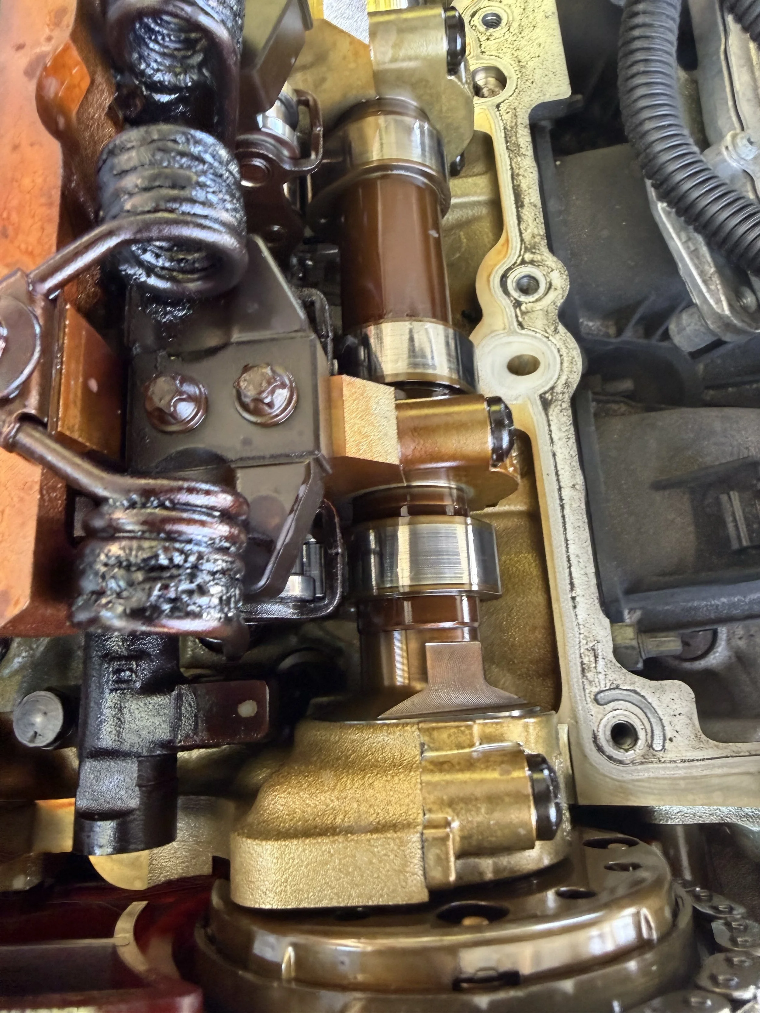 Close-up of an engine camshaft with timing chain and sprockets in an engine valve cover.