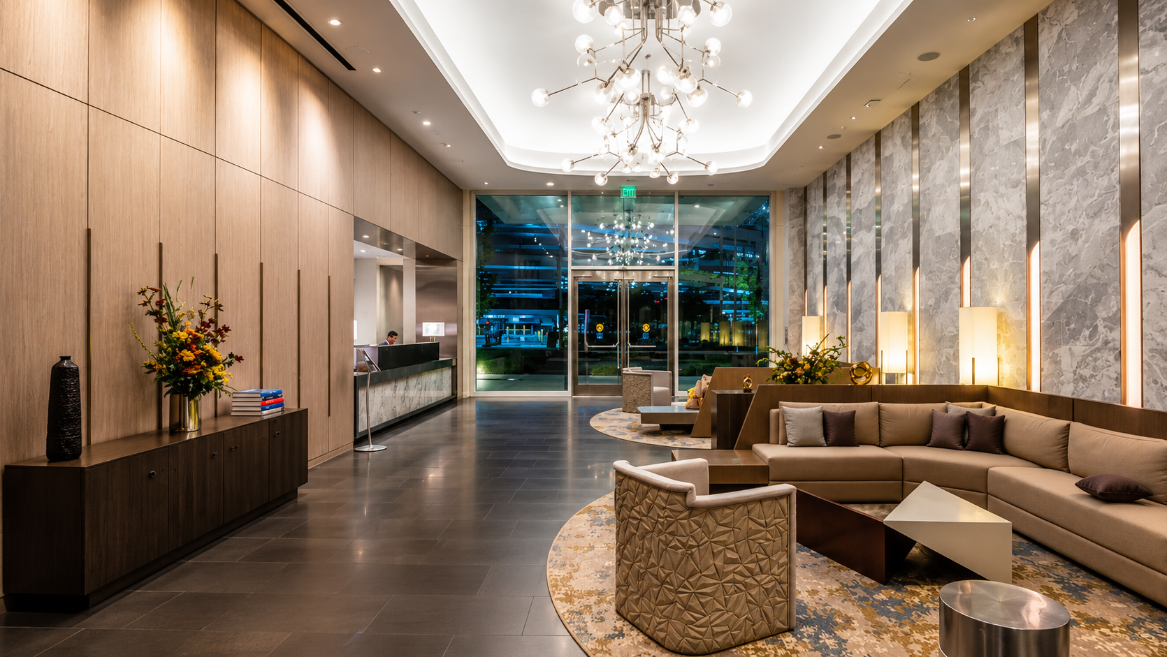Luxury hotel lobby with modern decor, wooden accents, large marble and stone wall, stylish lighting fixtures, and comfortable seating area.