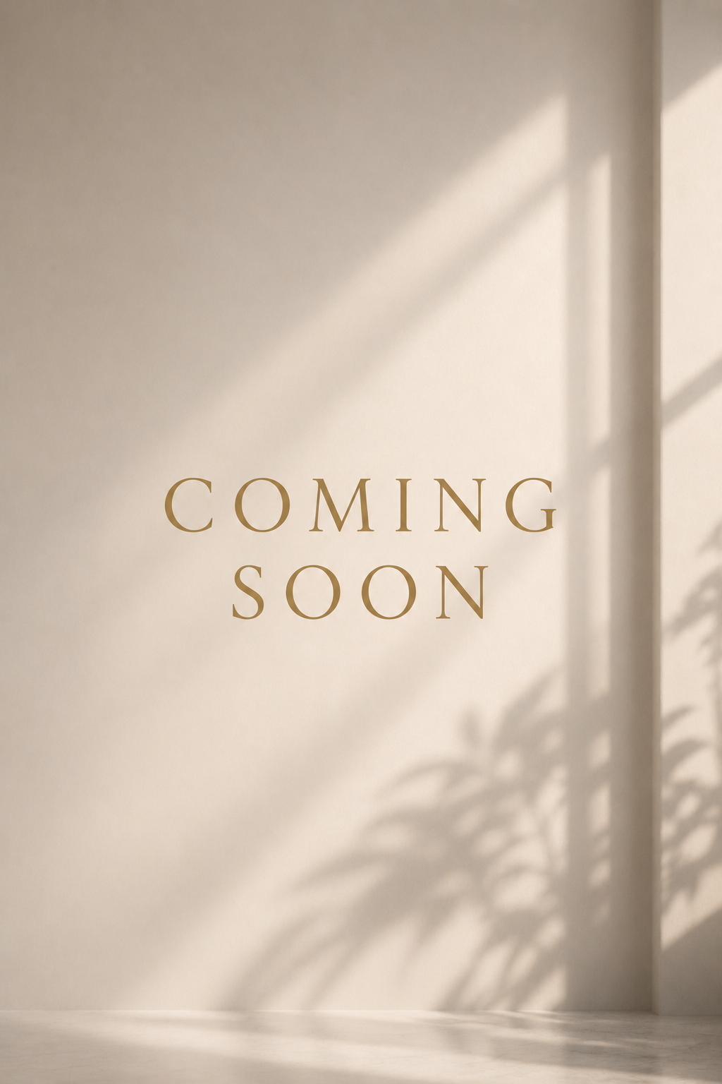 A wall with the words 'Coming Soon' in gold letters, sunlight casting shadows from nearby plants.