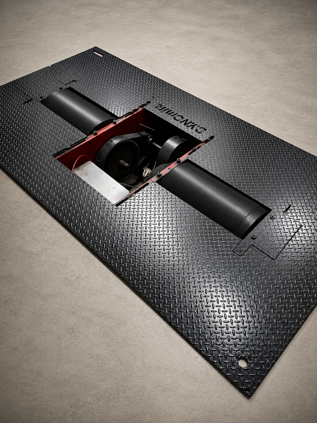 A black metal platform with a rectangular cut-out revealing machinery underneath, with the words 'PHYSICS MUSEUM' engraved on the surface.