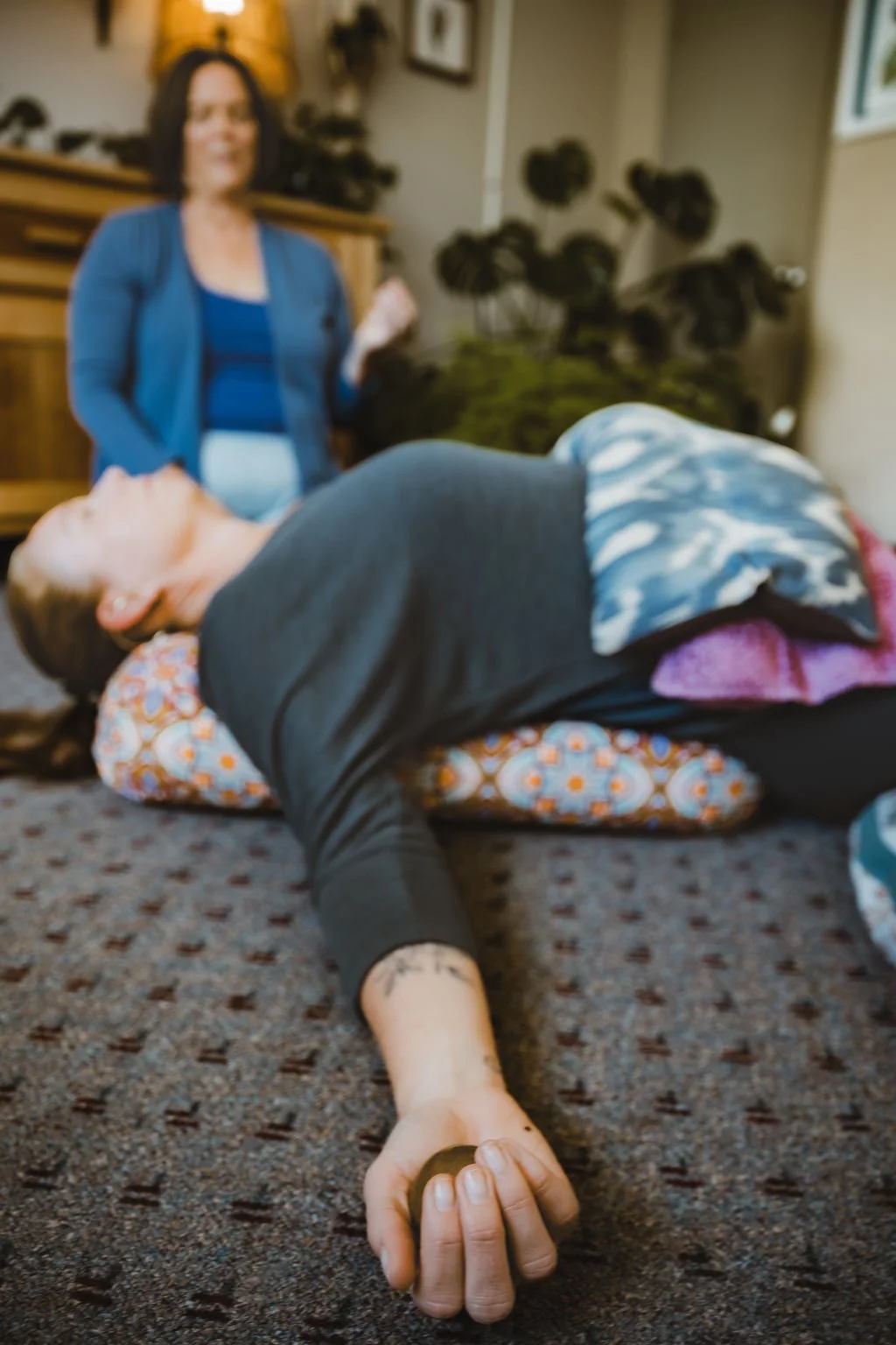 A woman lying on the floor with her eyes closed doing somatic exercises with Somatic embodiment Coach Heidi Andersen in Asheville