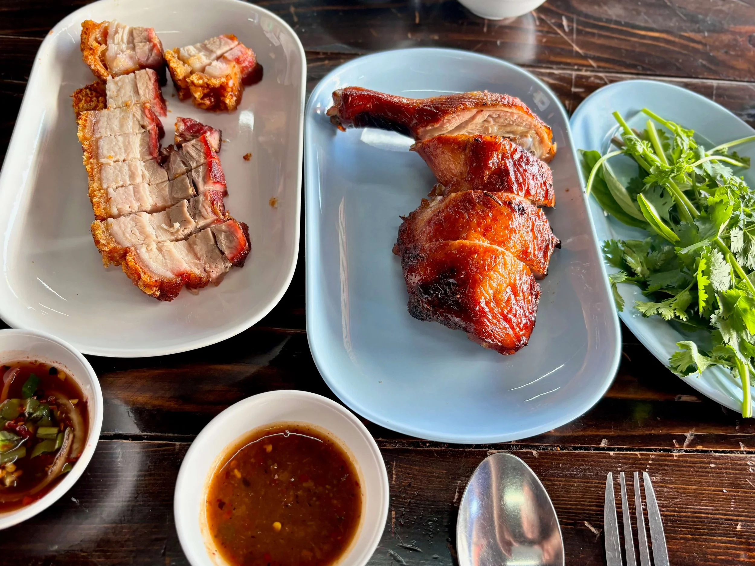 Barrel roasted chicken and pork belly served with cilantro and dipping sauce at Neng Mu Op Ong (Neng Roasted Pork) in Chiang Mai, Thailand