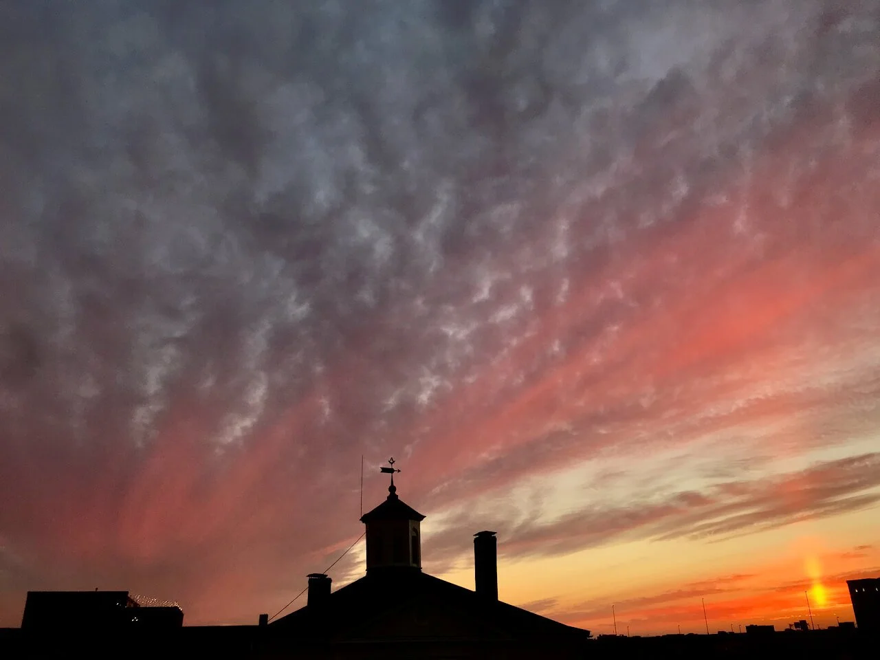 Pink and orange sunset sky over the Masons Hall's silhouetted cupola and weathervane, downtown Richmond, Virginia rooftops in view.