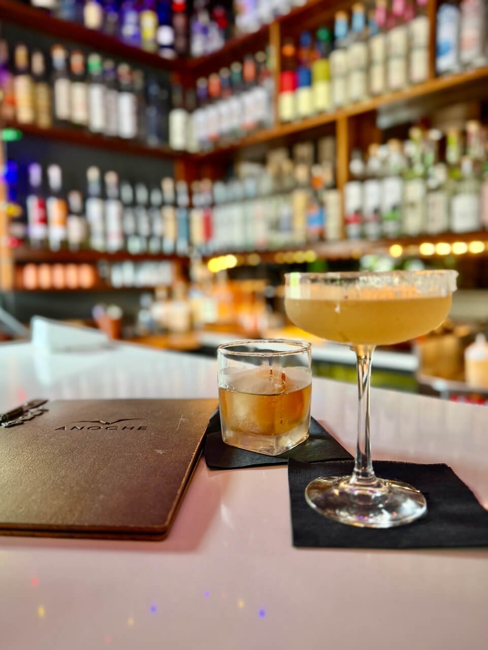Mezcal old fashioned and Saladito cocktail at Anoche, Asheville, floor-to-ceiling agave spirits shelf behind
