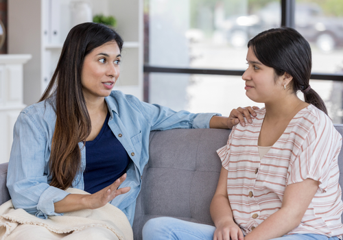 Mother and daughter talking on couch