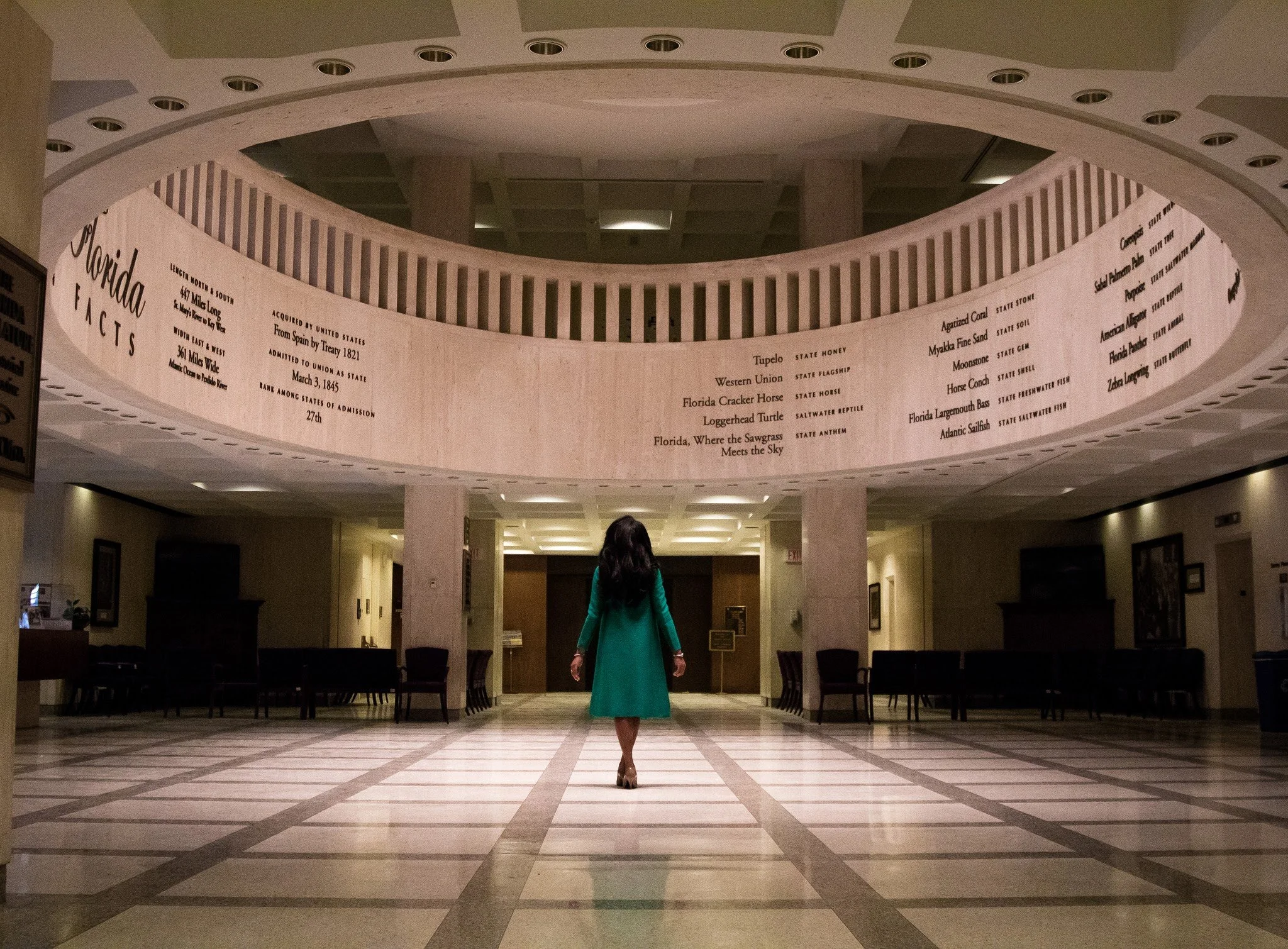 Black woman lobbyist, Florida capitol and a decorative banner with text about Florida's history and attractions.