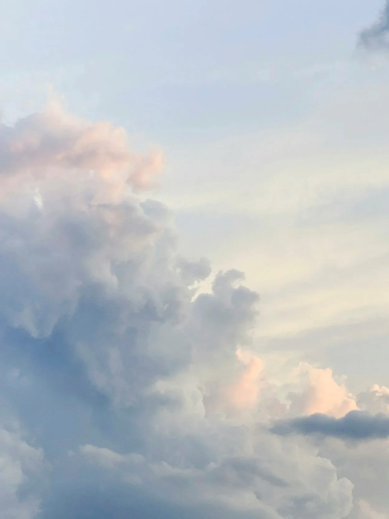 Sky filled with different shades of clouds, some pinkish, with a light, peaceful atmosphere.