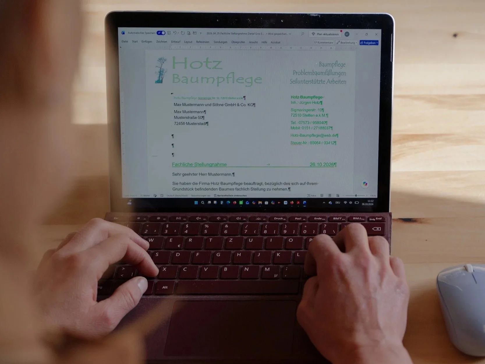 Person tippt auf einem Laptop an einem Word-Dokument über eine fachliche Stellungnahme zur Baumpflege.