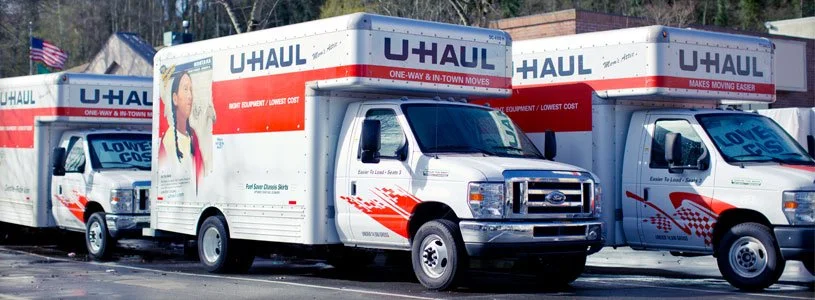 Three U-Haul moving trucks parked in a lot.