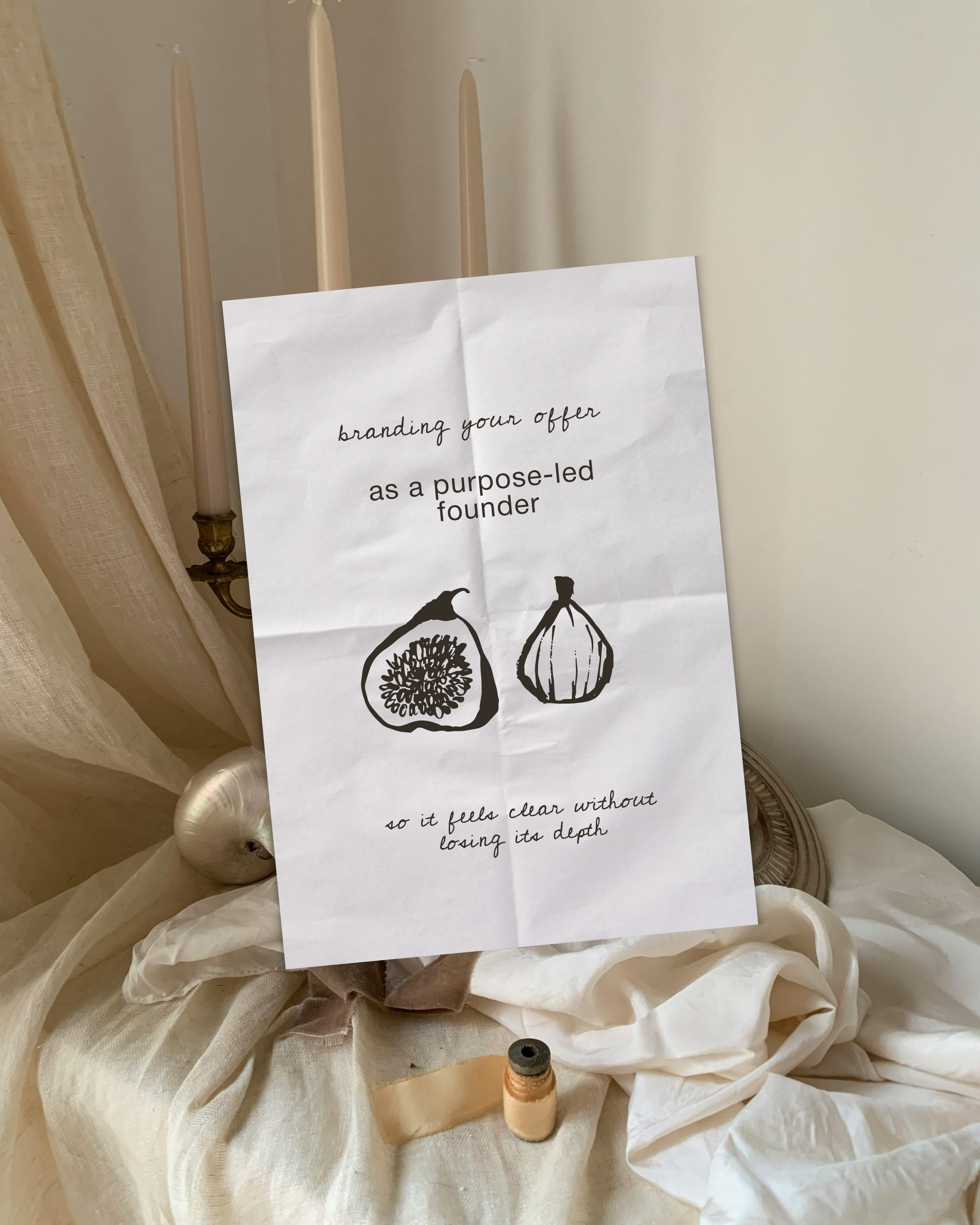 A white piece of paper with handwritten text and drawings, placed on fabric with neutral tones, including a small spool of thread at the bottom.