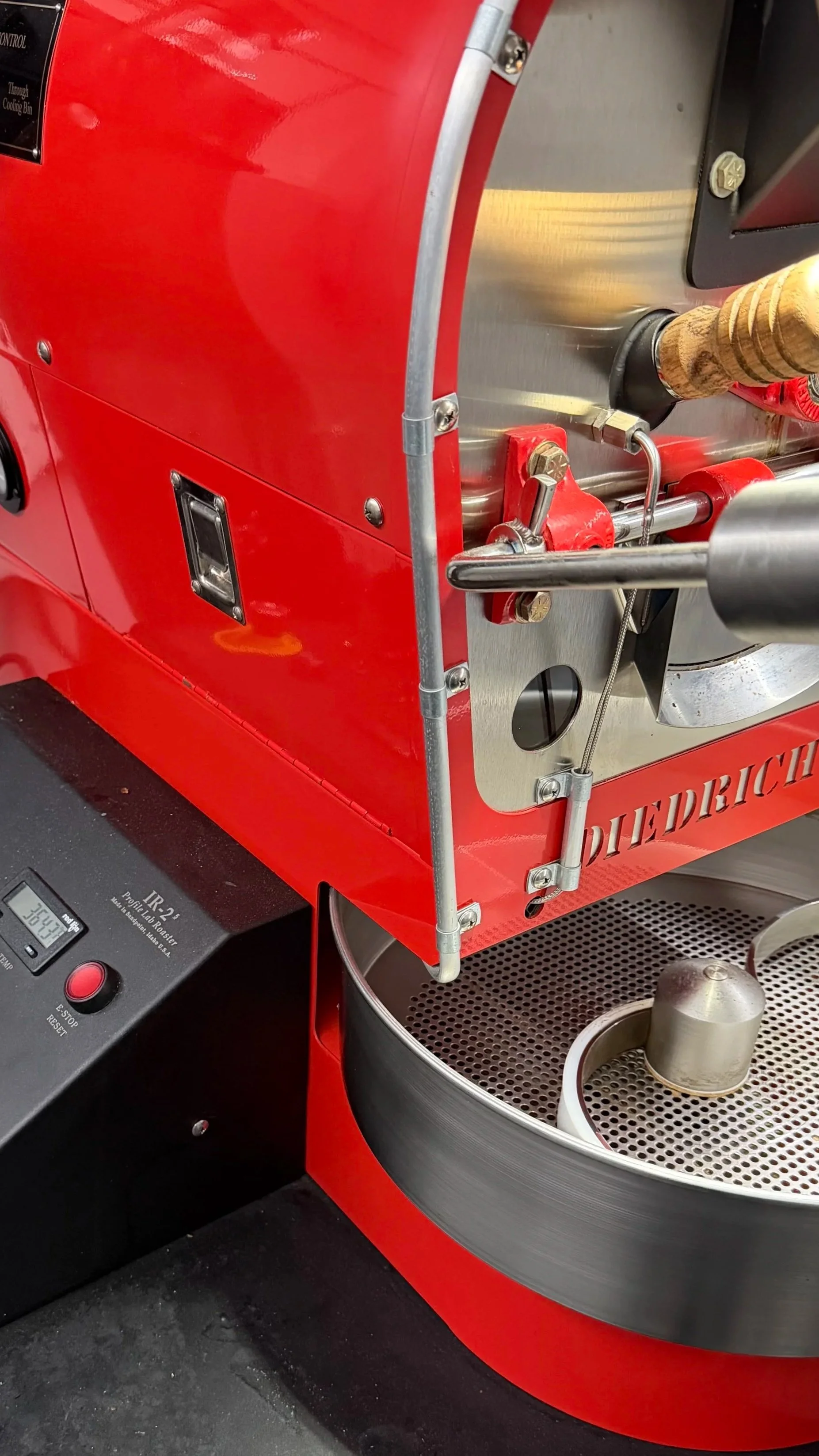 Close-up of a laboratory centrifuge machine with a red outer casing, a metal rotor with sample tubes, and control panel.