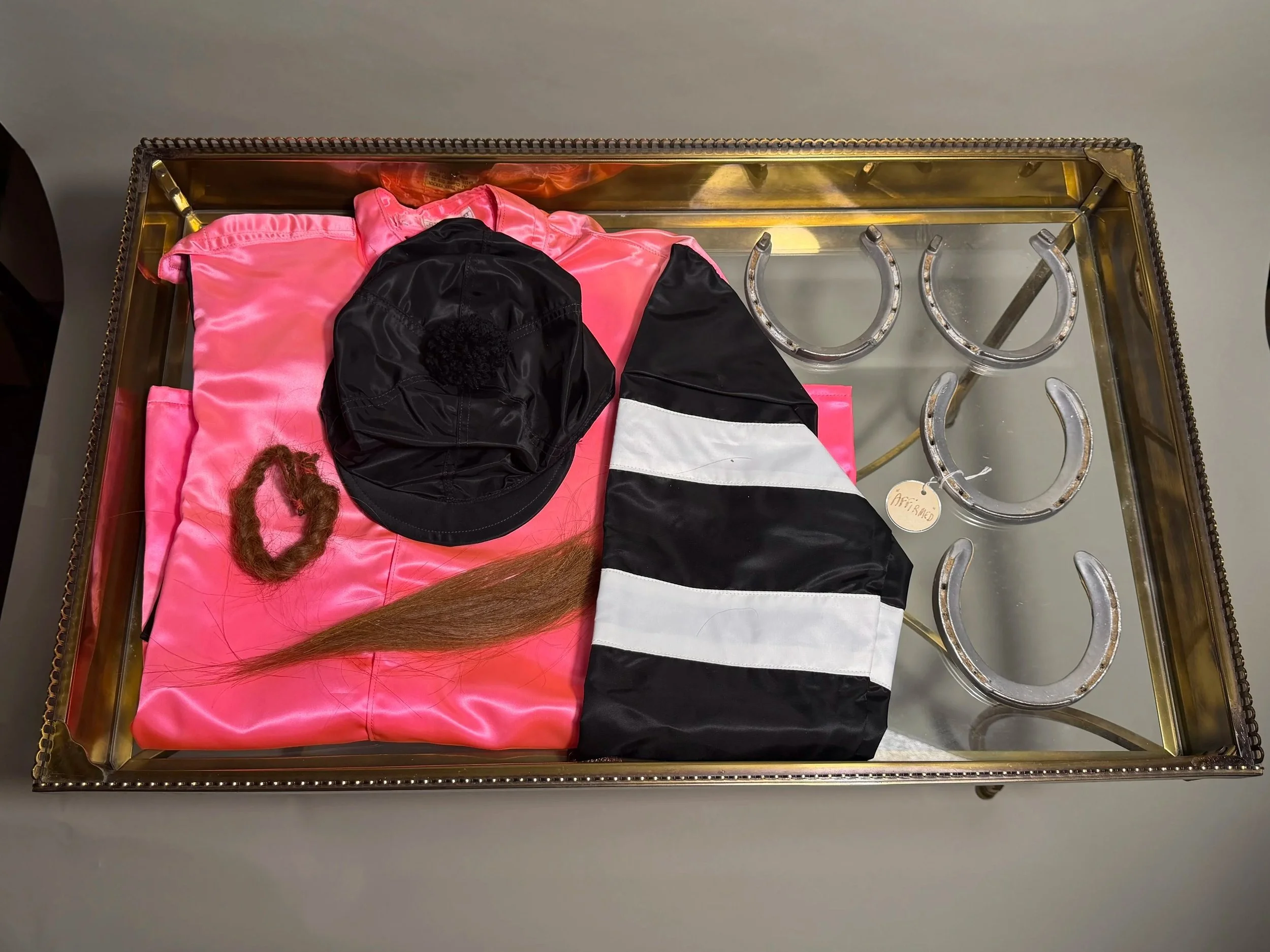 Affirmed's Harbor View silks, race-worn shoes,  and hair in display table from Patrice Wolfson