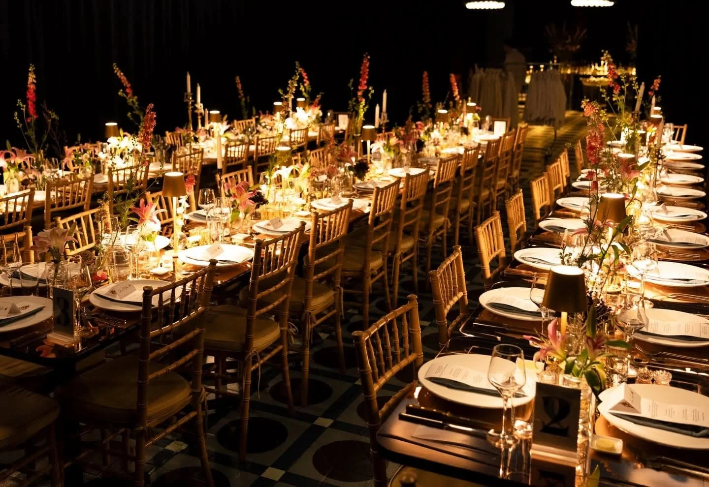 Elegant banquet table setup at Carton House event space in NYC with floral centerpieces, candles, and place settings in a dimly lit room.