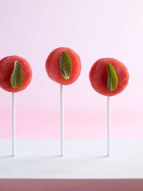 Watermelon Mint Lolipops arranged in a row against a light pink background.