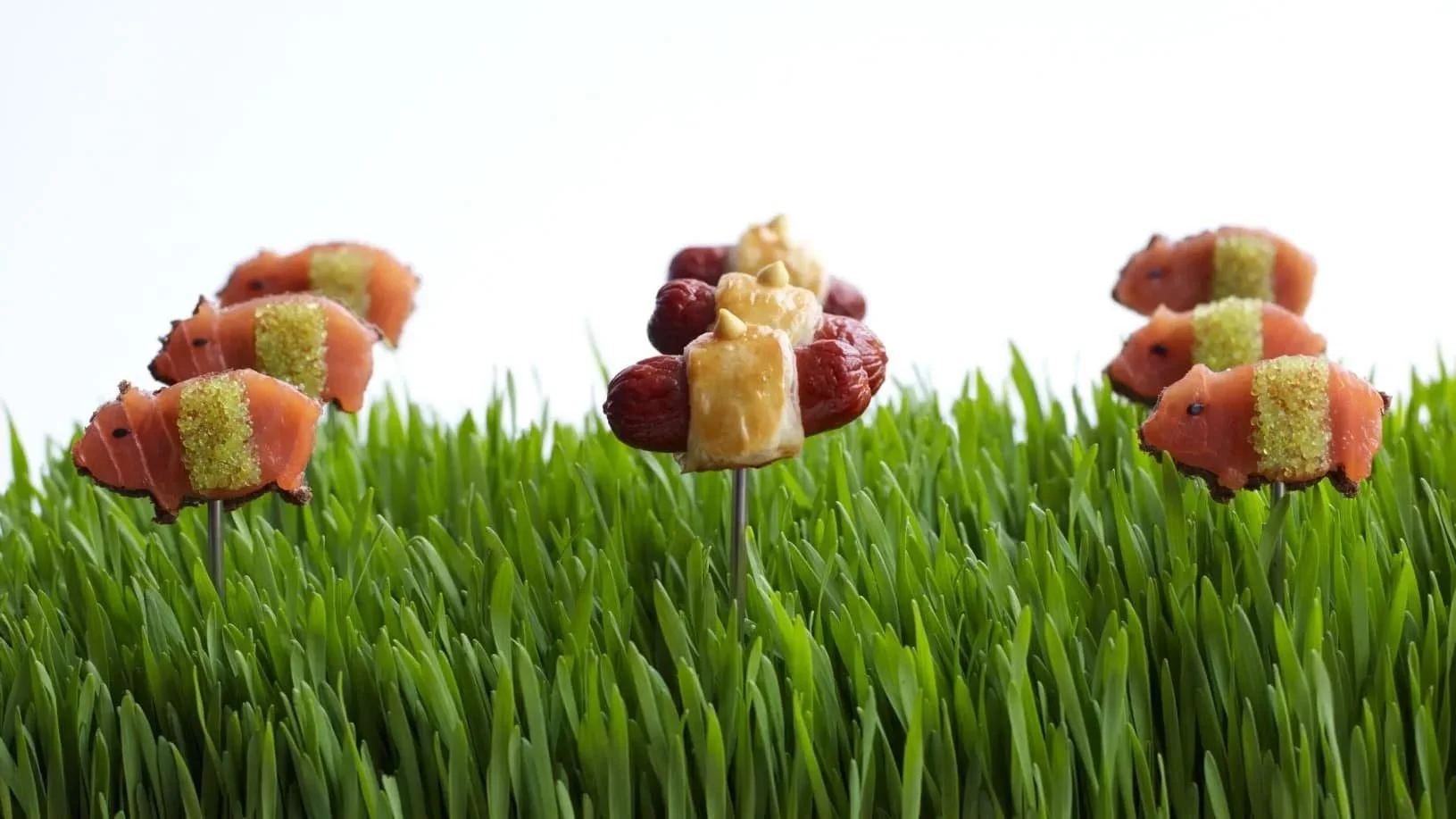 Miniature food sculptures, set on a bed of green grass.