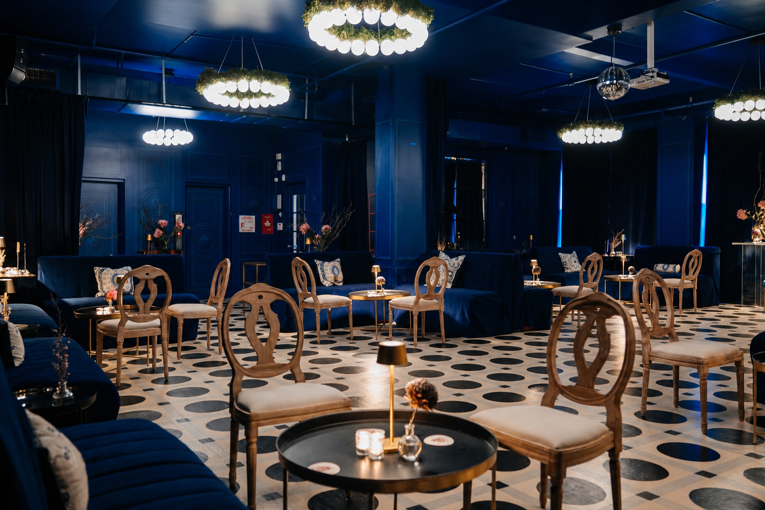 Elegant Carton House NYC event space with blue walls, velvet sofas, wooden chairs, small tables with lamps, and a black and white checkered floor.