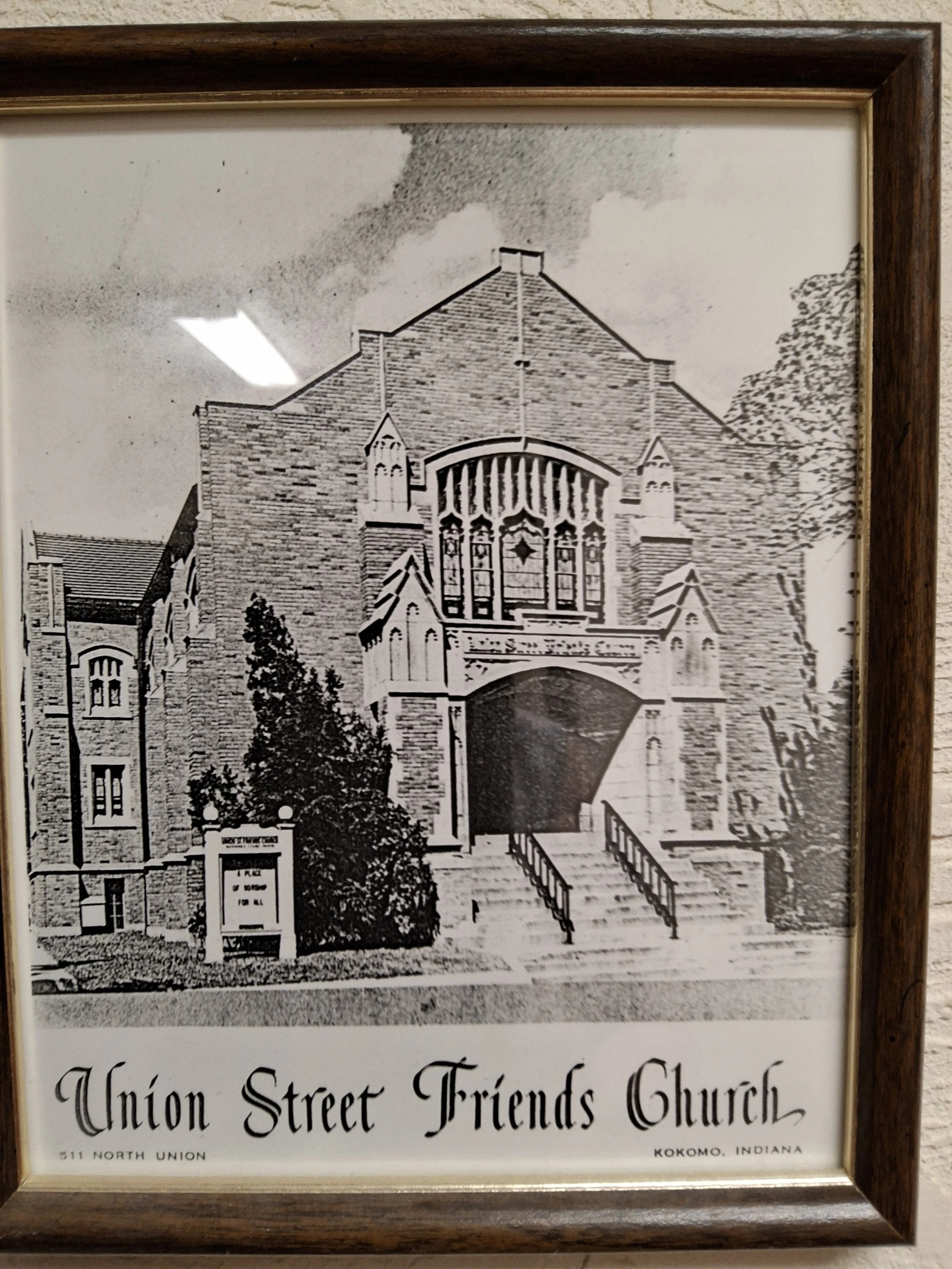 Photograph of a framed black-and-white illustration of Union Street Friends Church, located at 511 North Union, Kokomo, Indiana. The drawing shows the church's brick architecture, large stained-glass windows, and the surrounding trees.