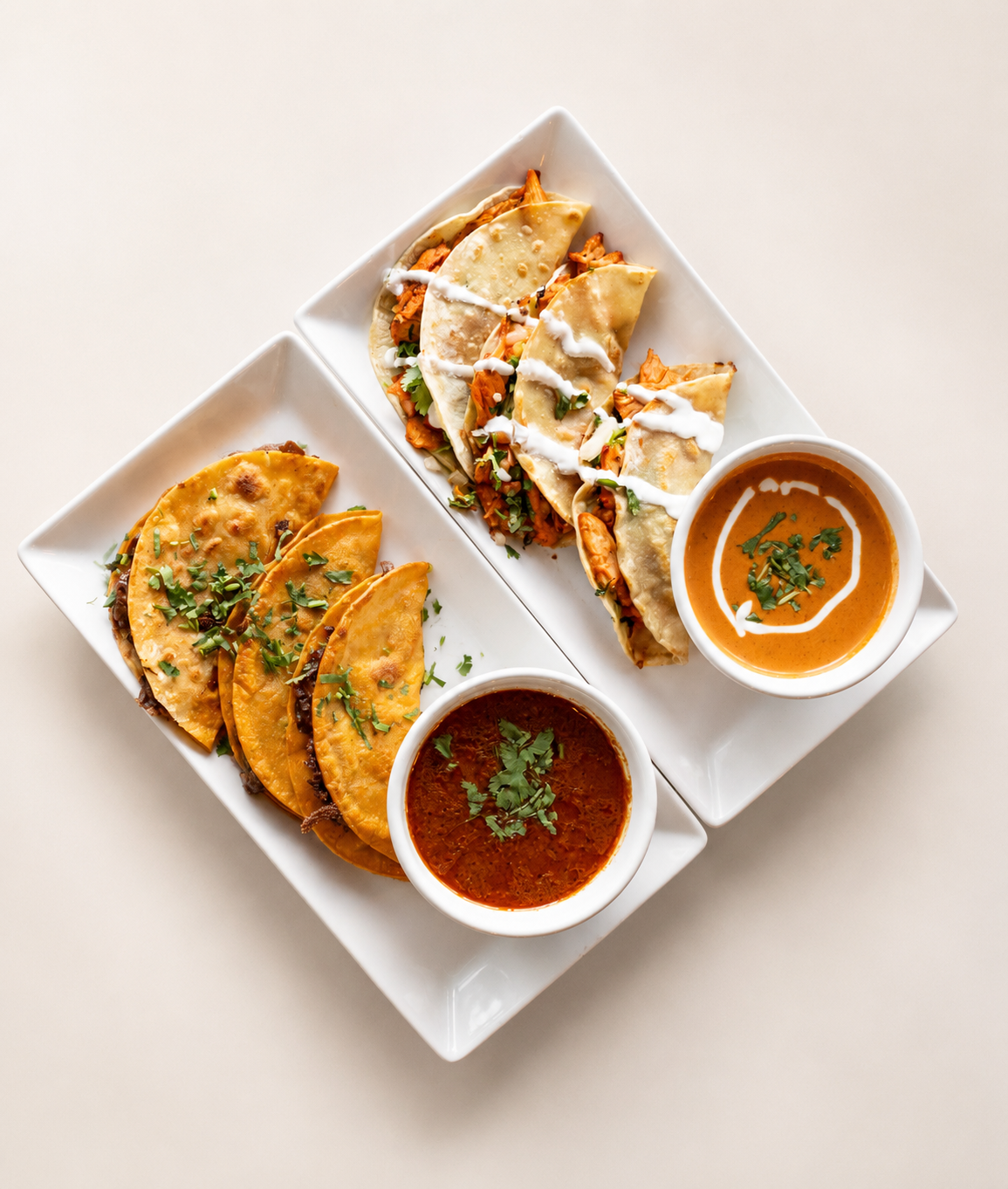 Plate of Indian-style tacos with two cups of curry, garnished with cilantro, on a white surface.
