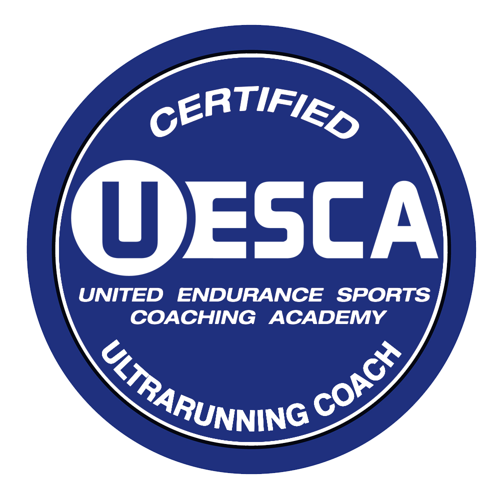 A circular badge with a blue background and white text reading "Certified UESCA" in the center, and "United Endurance Sports Coaching Academy" and "Ultrarunning Coach" around the edges.