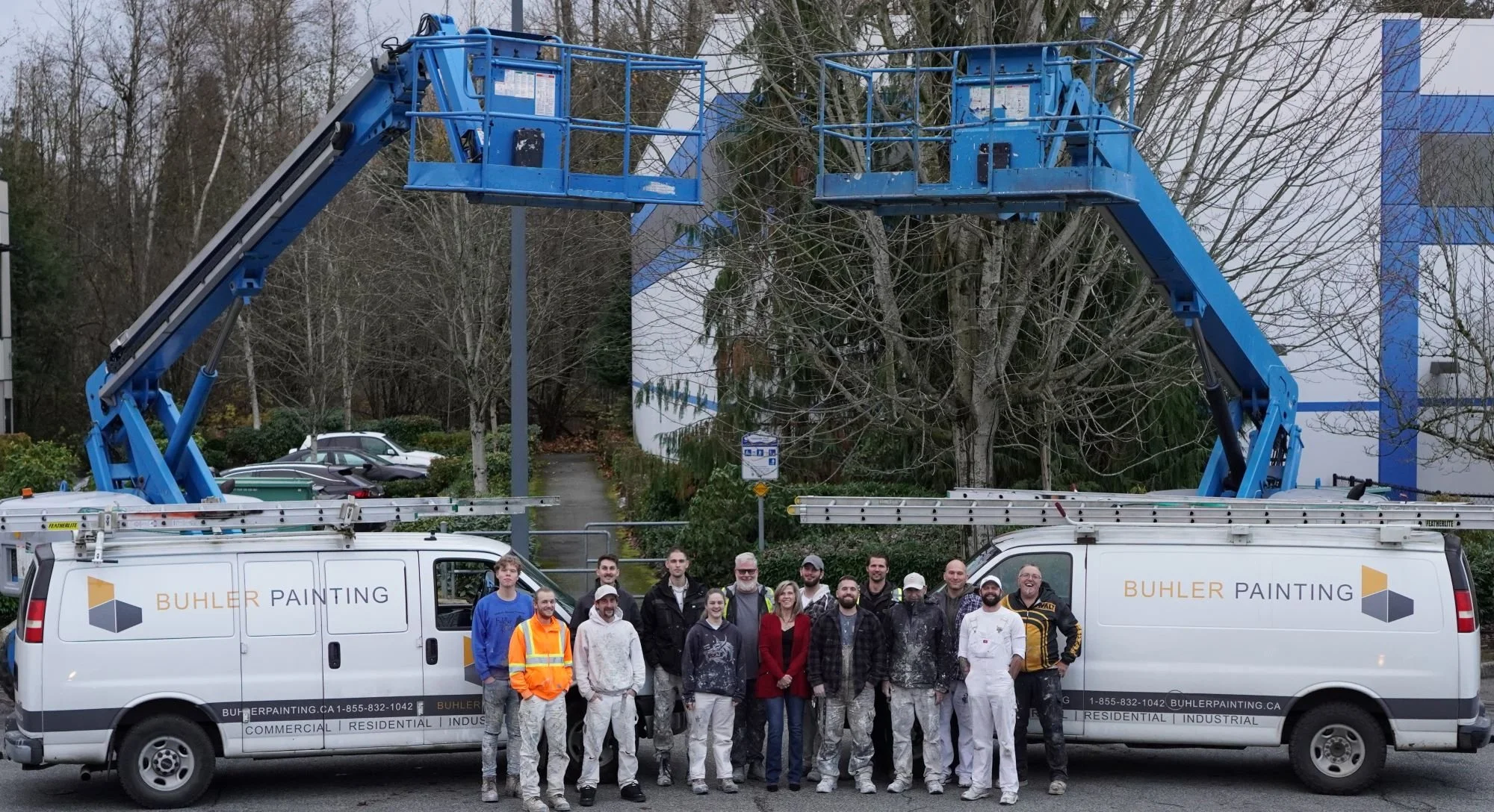 Buhler Painting local team photo of painters by two work vans with two genie lifts