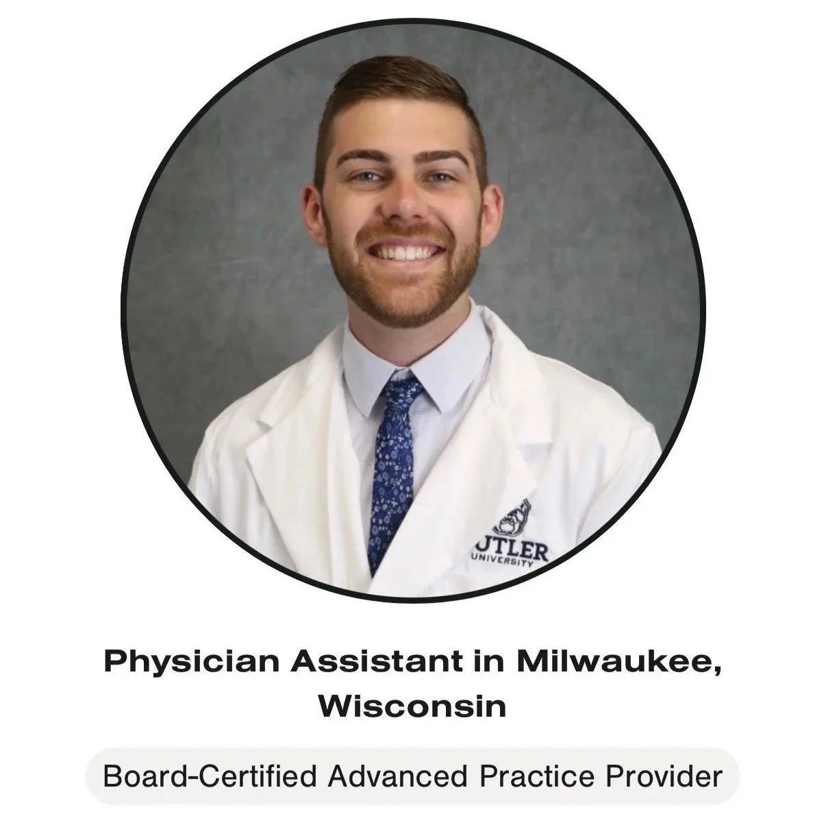Portrait of a smiling male healthcare professional wearing a white coat with university logo, standing against a grey background.