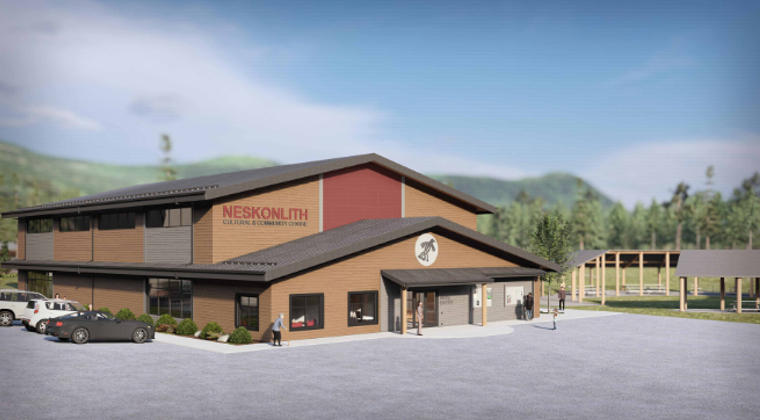 A multi-story building labeled Neskonlith Cultural and Community Centre with a large parking lot and some people walking nearby, in a rural area with hills and trees in the background.