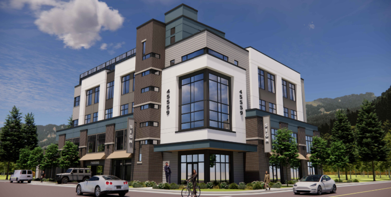 A modern multi-story commercial building with large glass windows, surrounded by parked cars, bicycles, and trees, with a mountain backdrop.