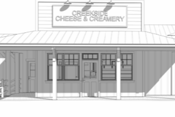 Front view of Creekside Cheese & Creamery storefront with a sign, windows, door, and exterior lighting
