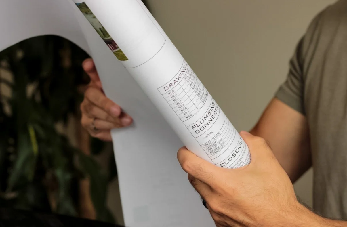 Person holding a rolled-up blueprint or architectural plan.