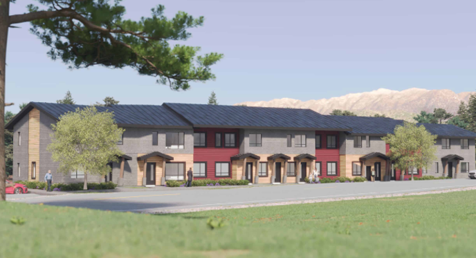 A row of modern townhouses with gray and red exteriors, multiple entrances with canopies, and landscaping including trees and grass, under a clear sky with distant mountains.