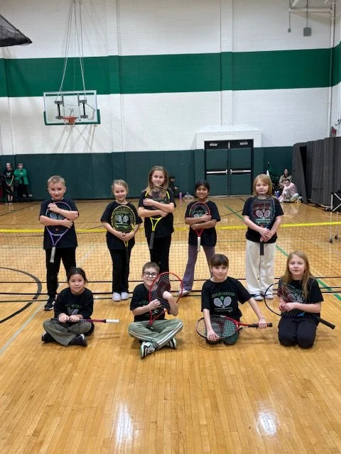 Young children in a gymnasium holding jump ropes and foam sticks, posing for a group photo.