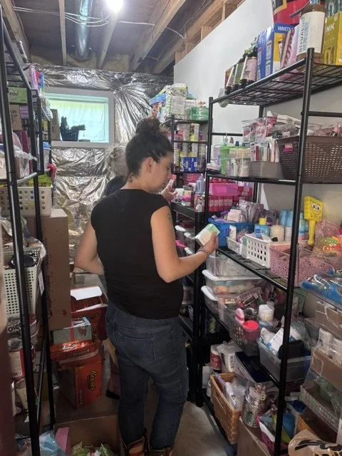 A woman shopping in a storage room with shelves filled with household and craft supplies.