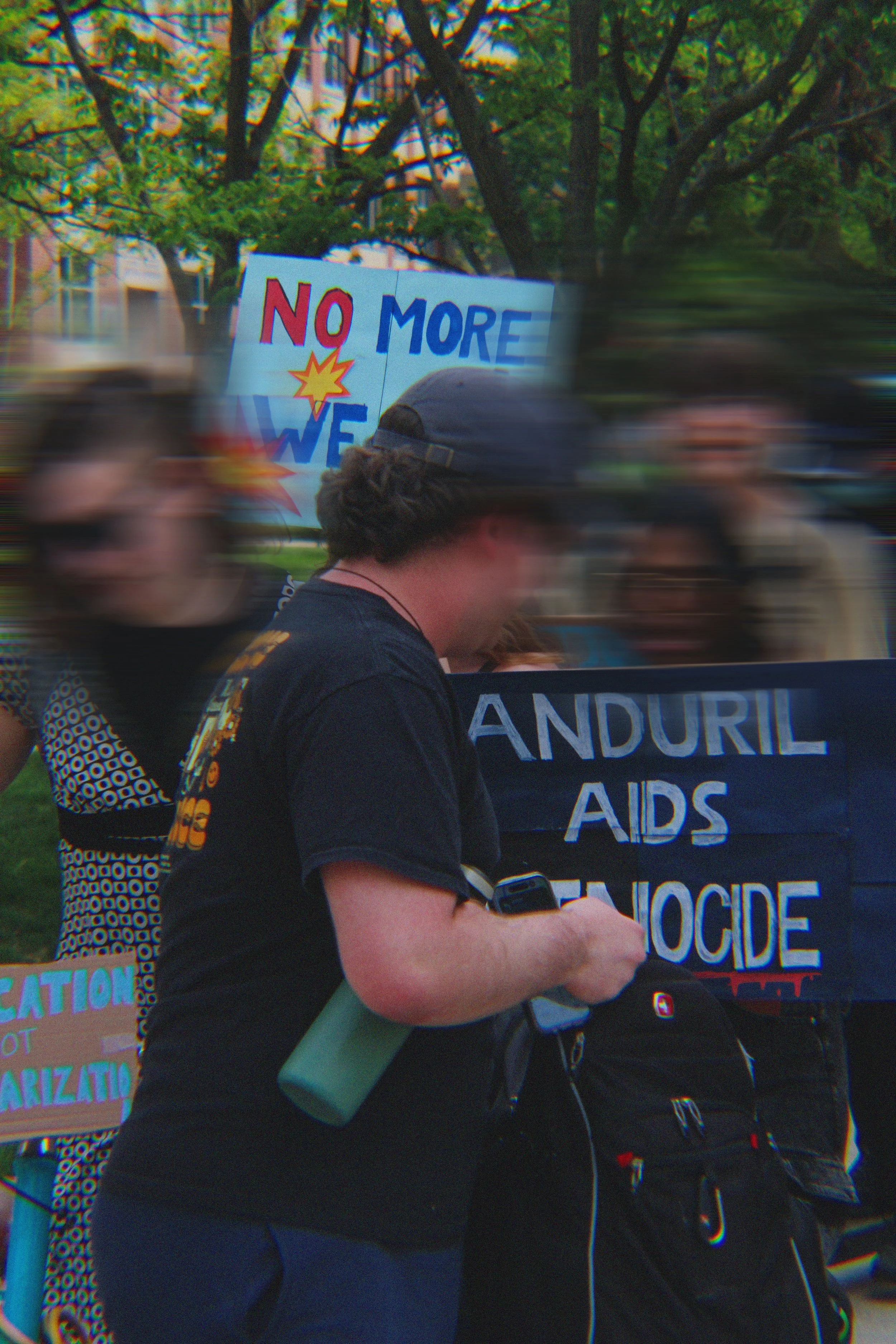 People walking outdoors during a protest or rally, holding signs and banners related to AIDS awareness.