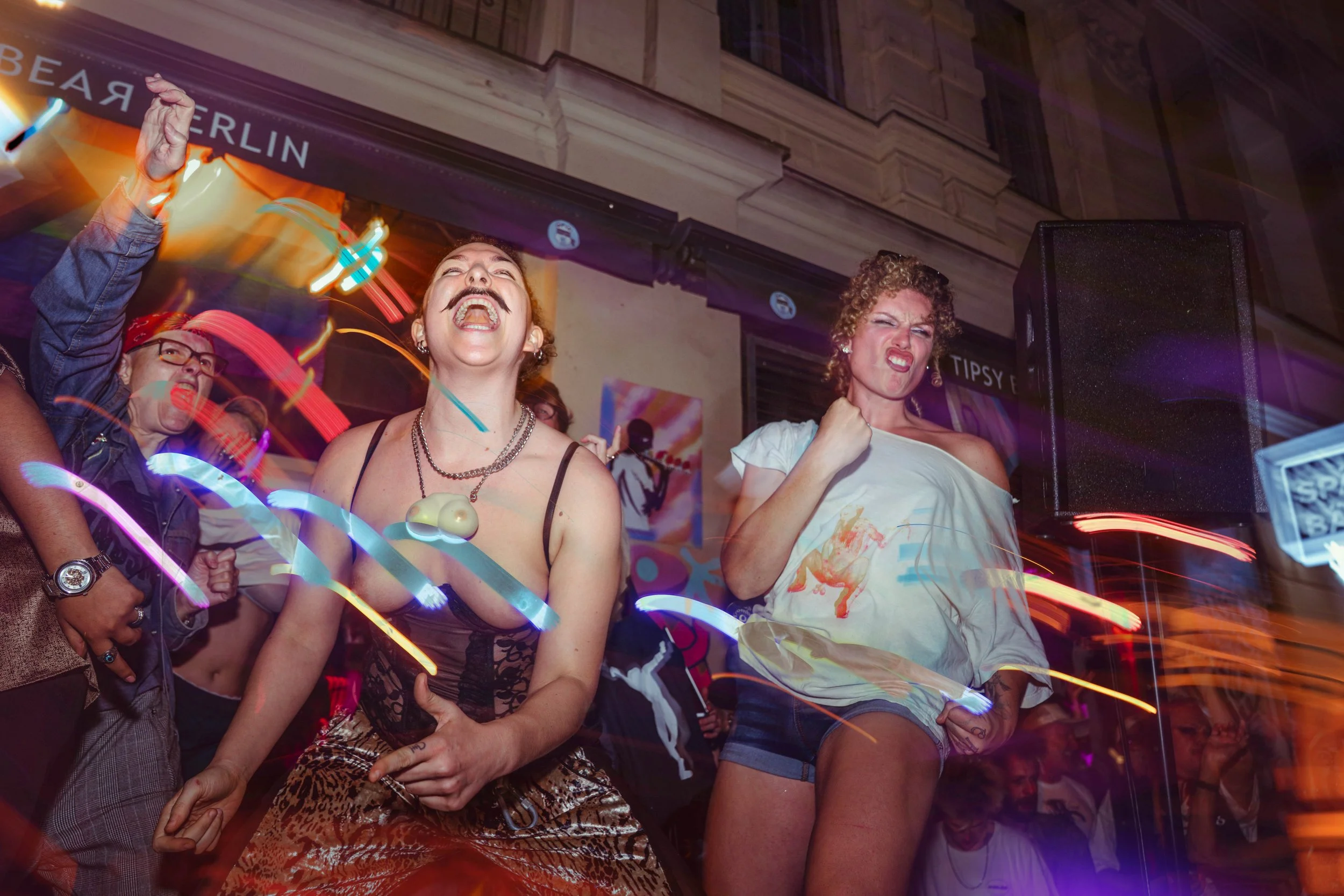 People dancing and celebrating at a lively party or nightclub with colorful lights and vibrant atmosphere.