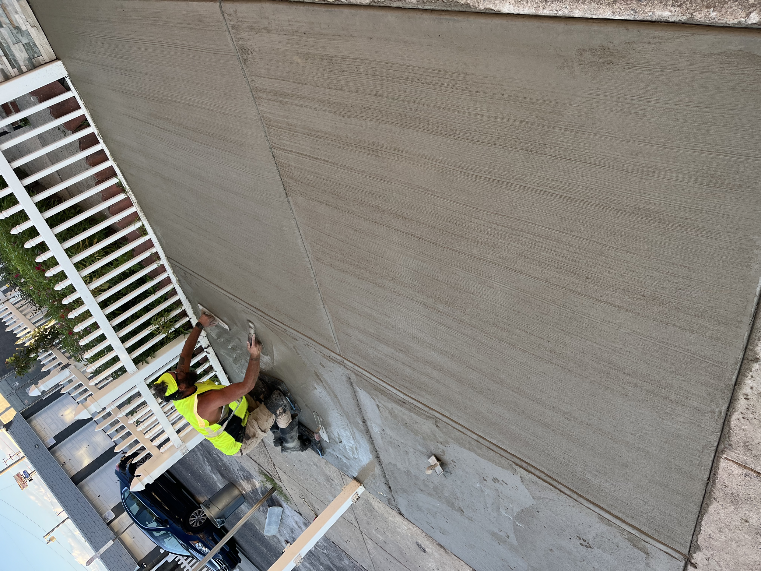 A construction worker applying a concrete coating to a wall with a trowel.