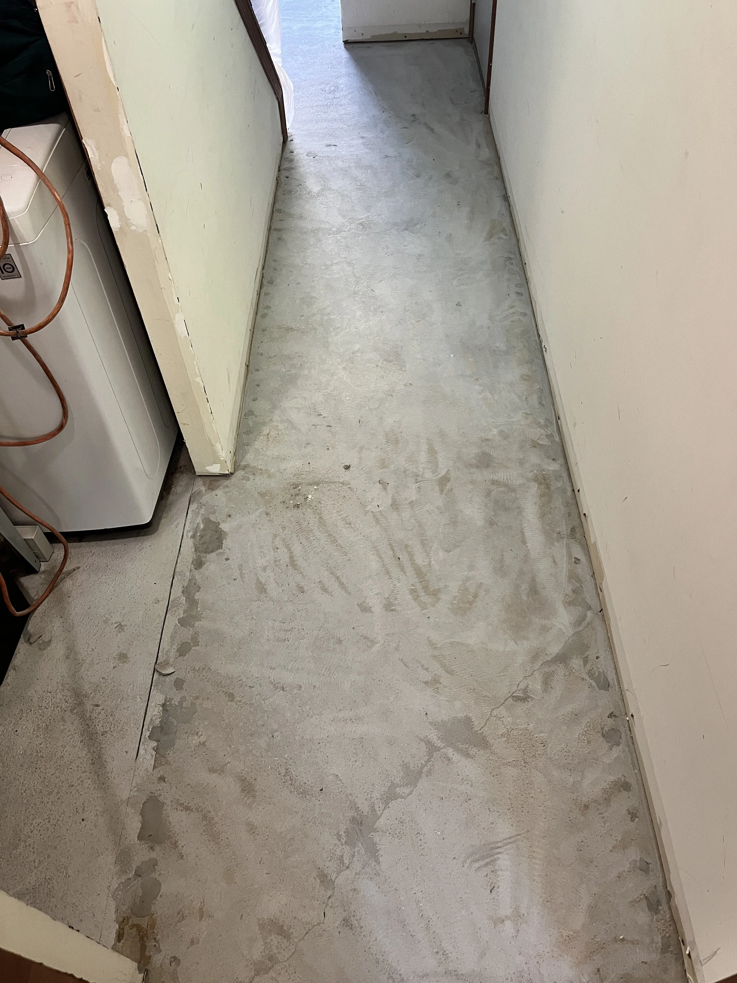 Unfinished interior room with concrete floor, walls partially painted, and some construction materials and tools visible.
