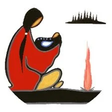 A woman in traditional attire sitting cross-legged, holding a baby in her lap, with a city skyline in the background and a flame or light source nearby.