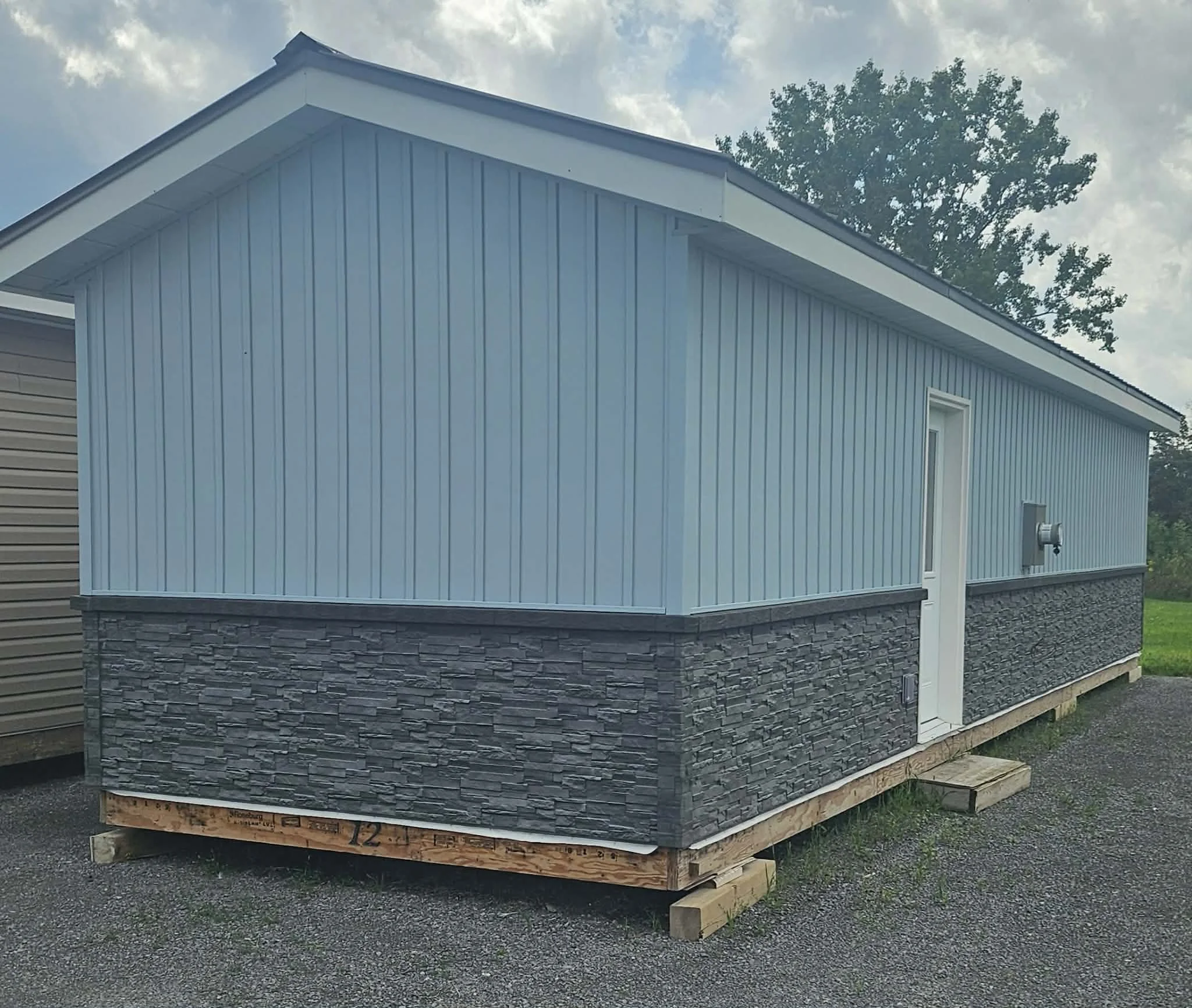 Blue vinyl siding modular house on wooden foundation supports