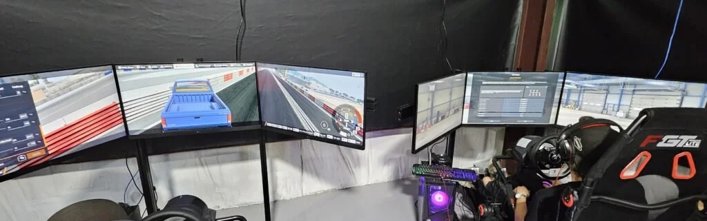Three-monitor driving simulator workstation with steering wheel and controls