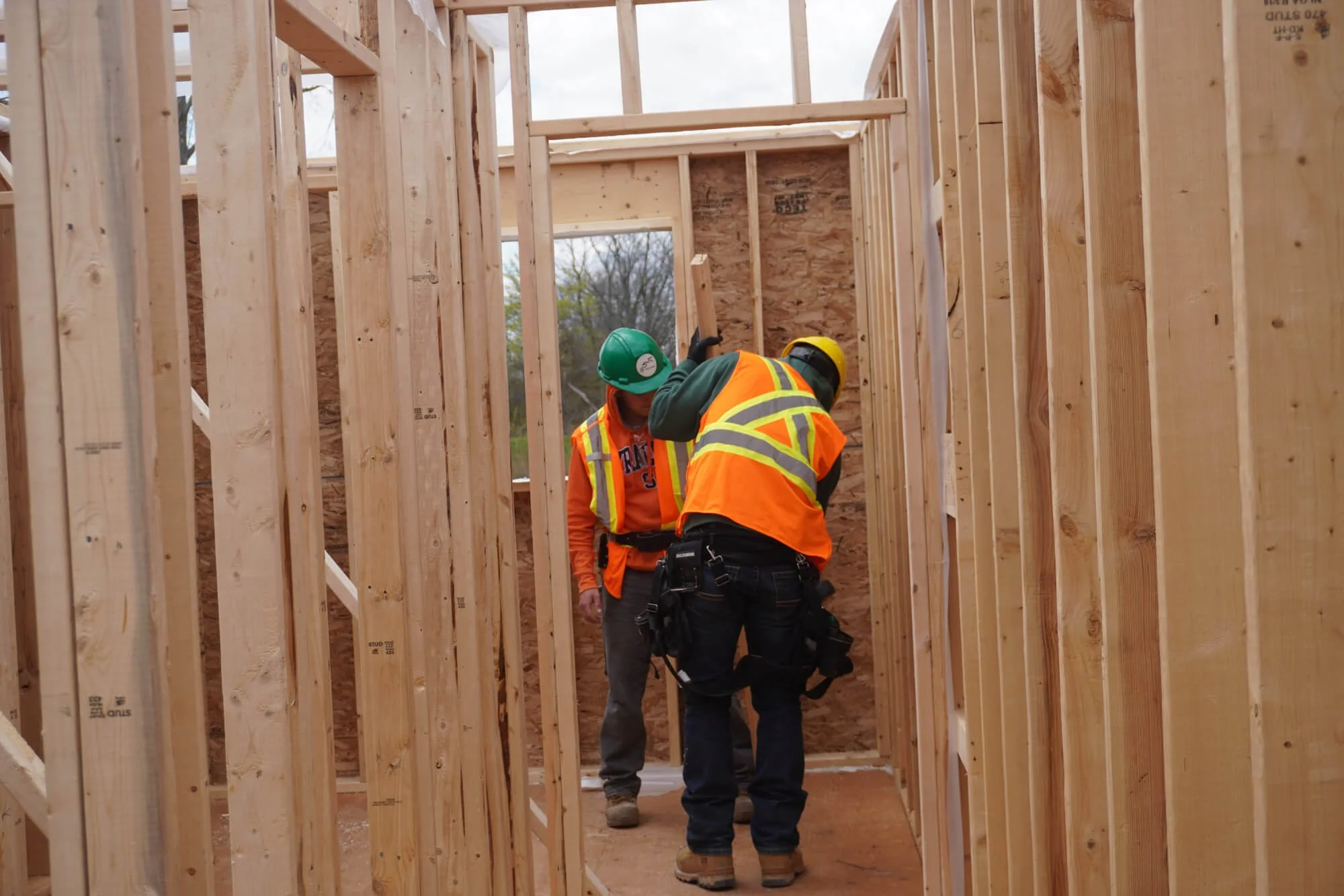 Indigenous construction trainees in safety gear inspecting a wooden building frame during an ALFDC skilled trades program.