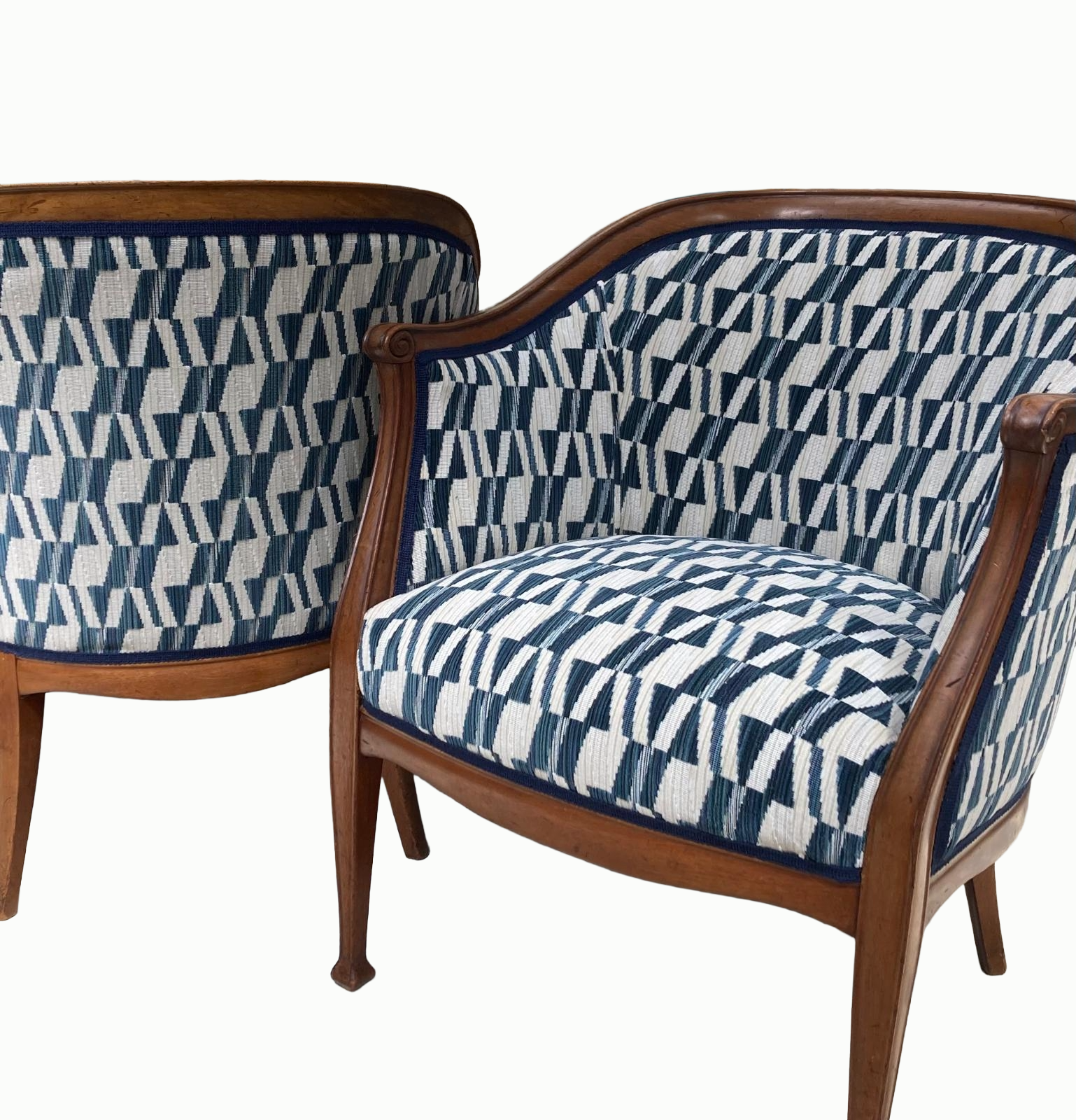 Two vintage wooden armchairs with upholstered seats and backs, featuring a blue,white, and black geometric pattern. One chair is facing forward, and the other is turned to the side.