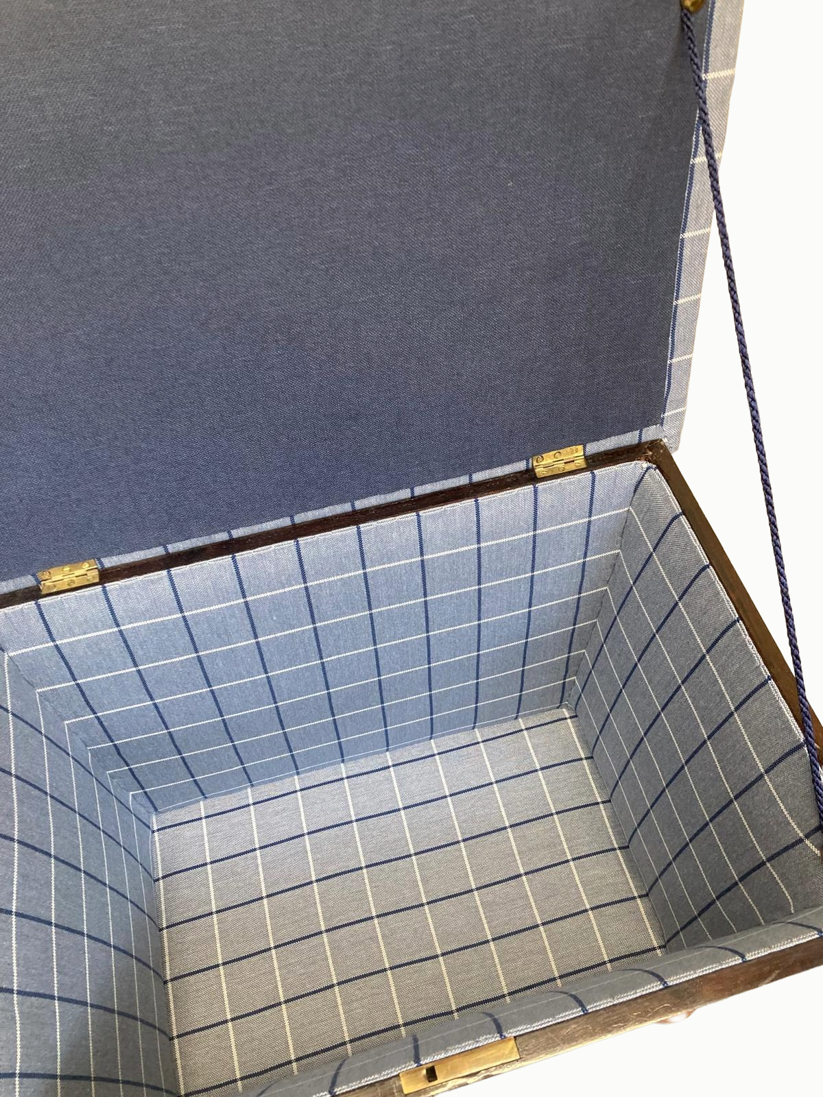 Open rectangular box with a blue and white checked fabric lining on the inside and plain blue fabric on the outside.