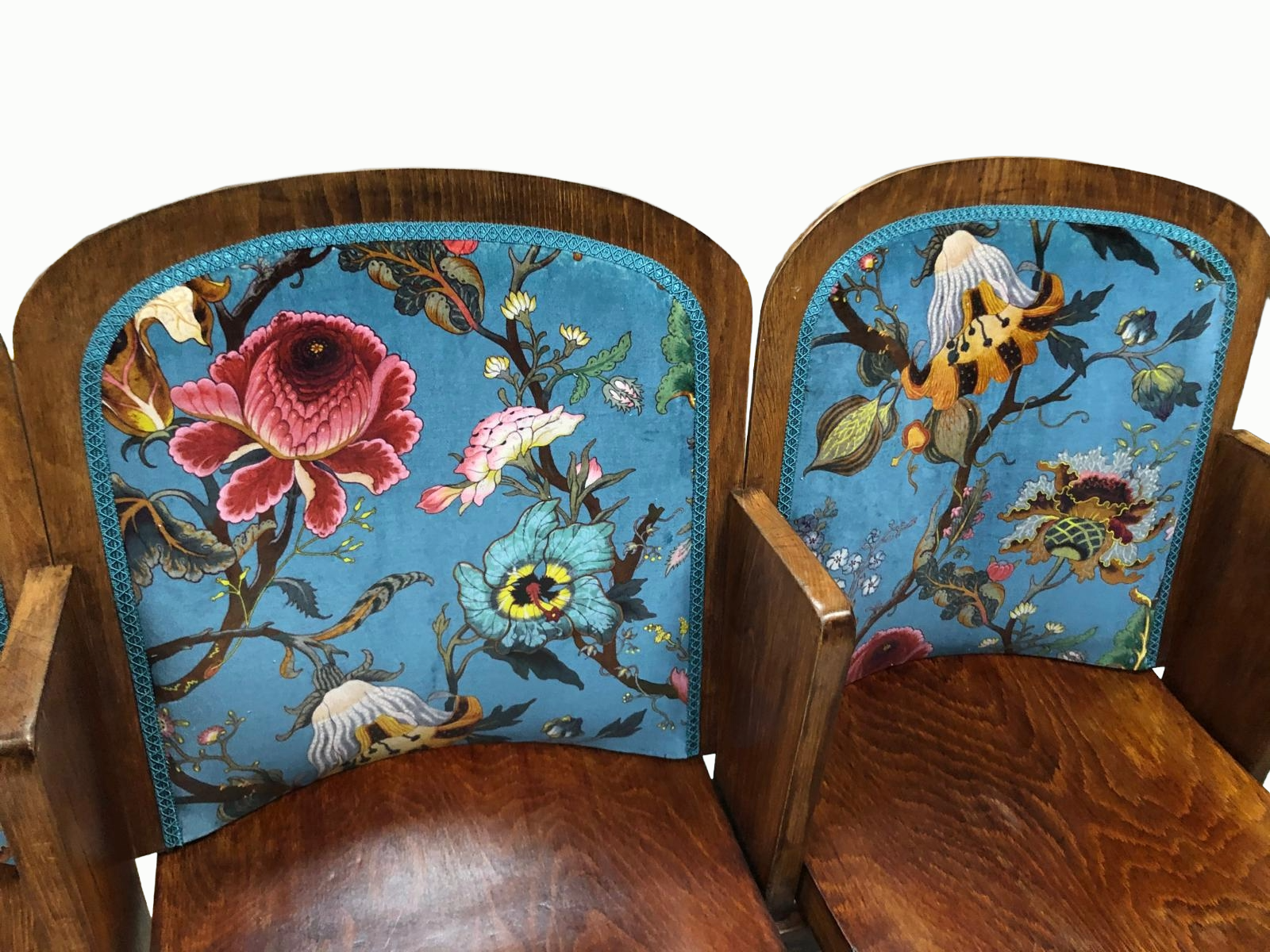 Close-up of two cinema seats with upholstery featuring colorful floral and bird designs on a blue background.