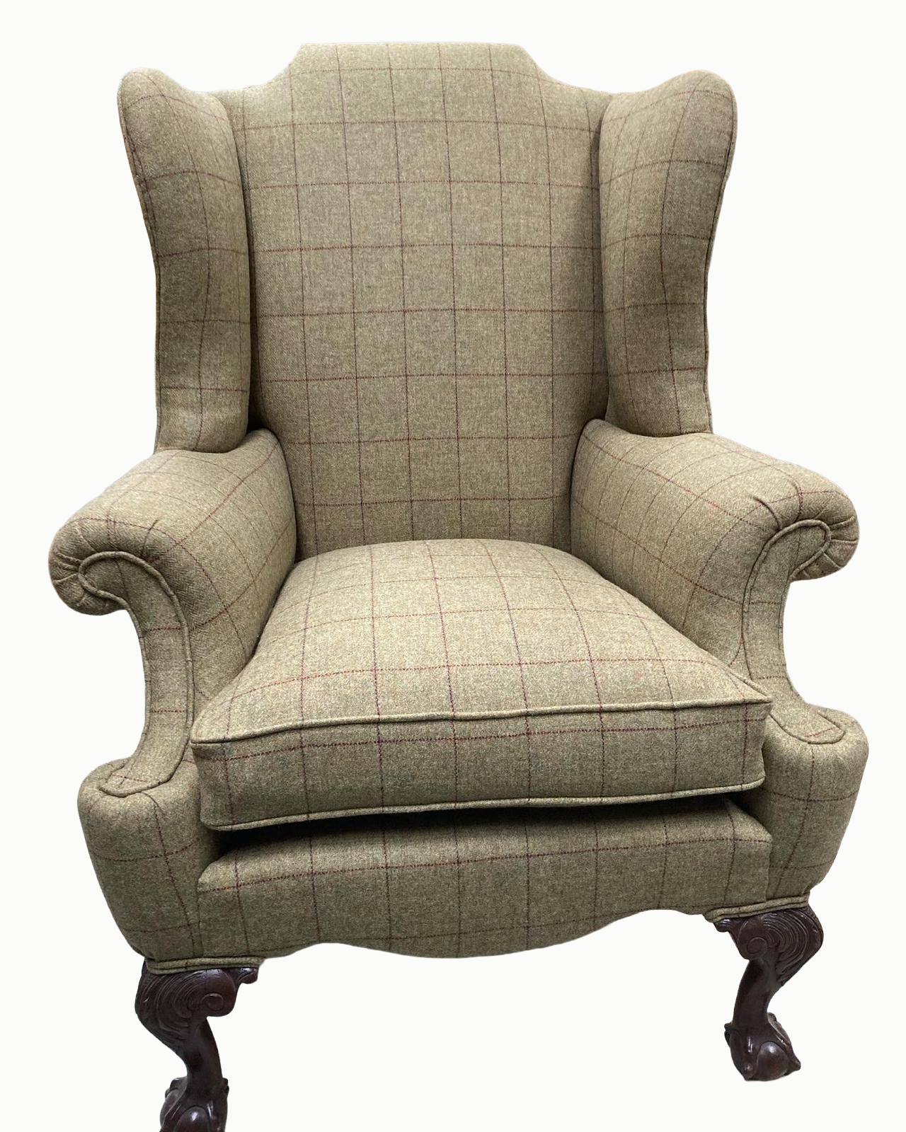 A vintage high-back wing chair with plaid upholstery and dark wooden carved legs.