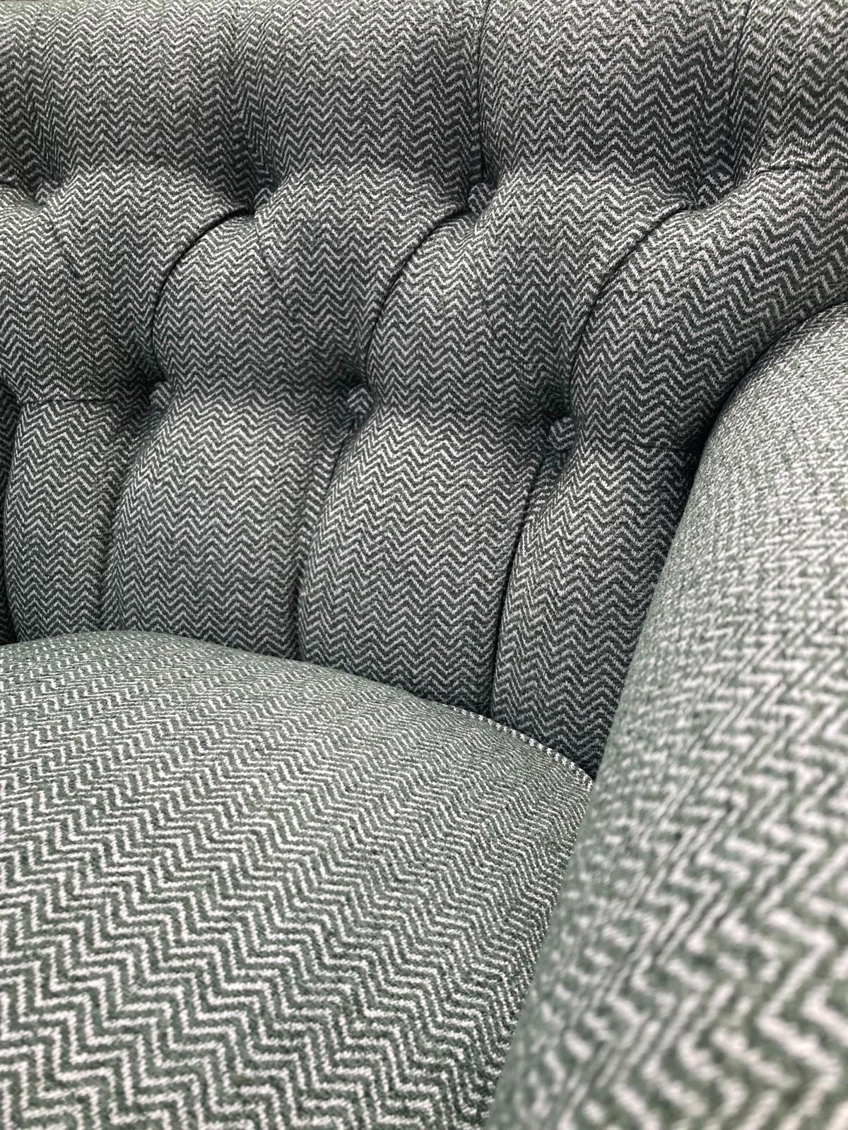 Close-up of a tufted armchair with black and white zigzag patterned upholstery.